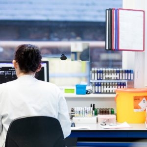 Supporting Ground breaking Research: "A researcher in a lab coat working at a bench with rows of test tubes in a laboratory