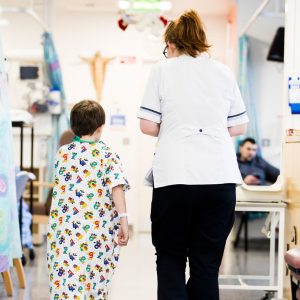Laparoscopy Tower: "A nurse guiding a young patient in a hospital gown through a hospital ward