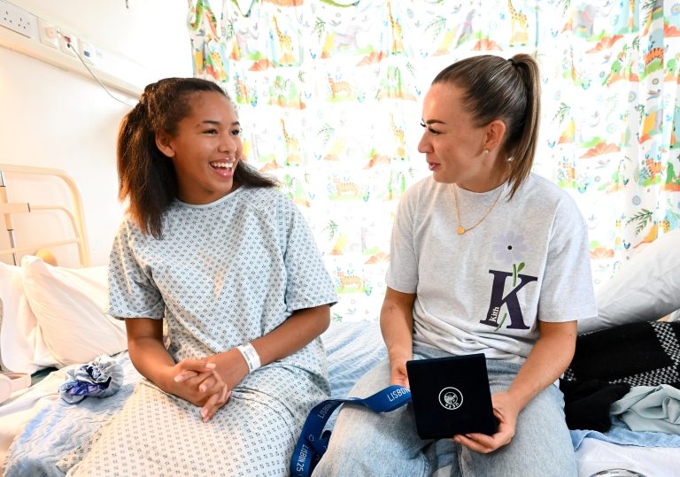 Katie McCabe in smiling in hospital with patient