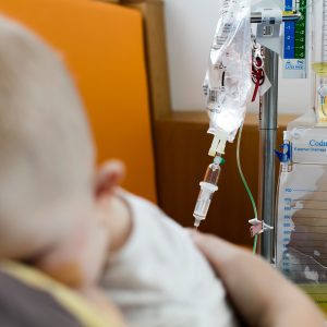 Efficia Cardiac Monitors: "A close-up of an IV drip line with a patient's arm in the background in a hospital room
