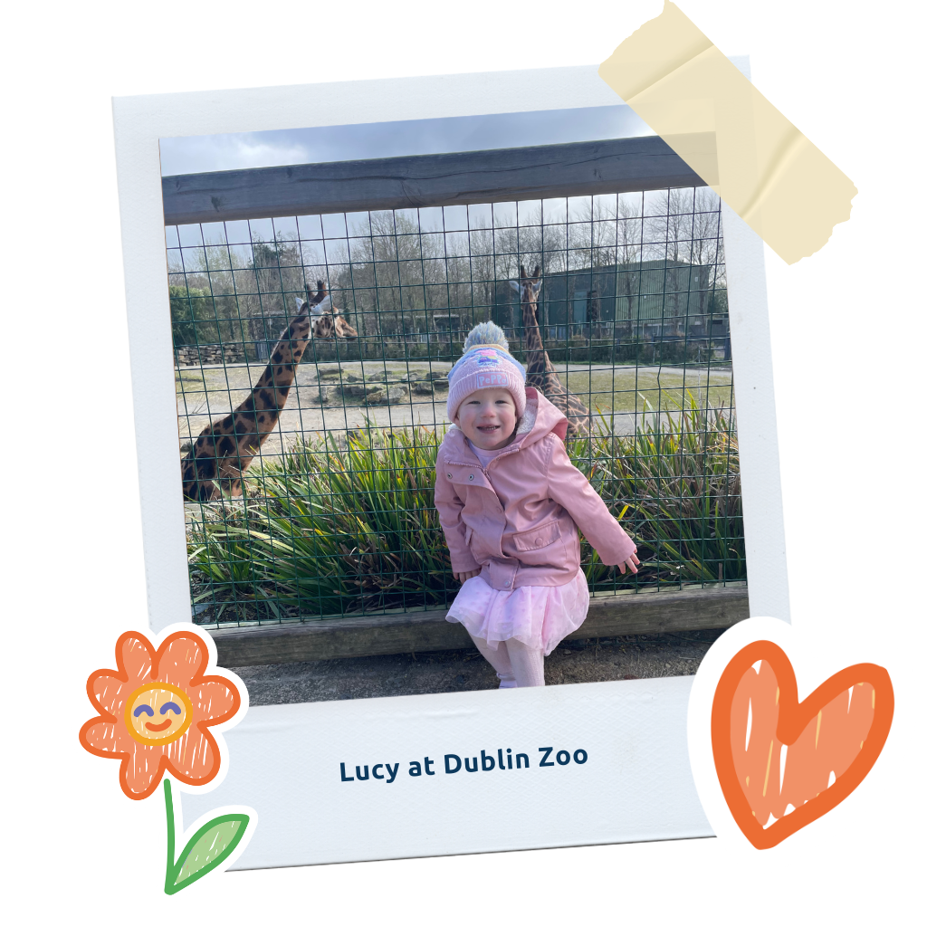 Lucy_LP_Thumb: "A polaroid-style photo of Lucy in a pink coat at Dublin Zoo.