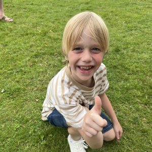 Meet the kids Freddies: "A smiling boy standing on grass outdoors."