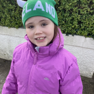 Roisin: "Róisín in a purple coat and green bobble hat outdoors."