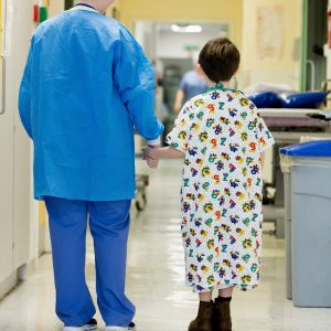down syndrom: "A nurse in scrubs walking down a hospital corridor with a child."